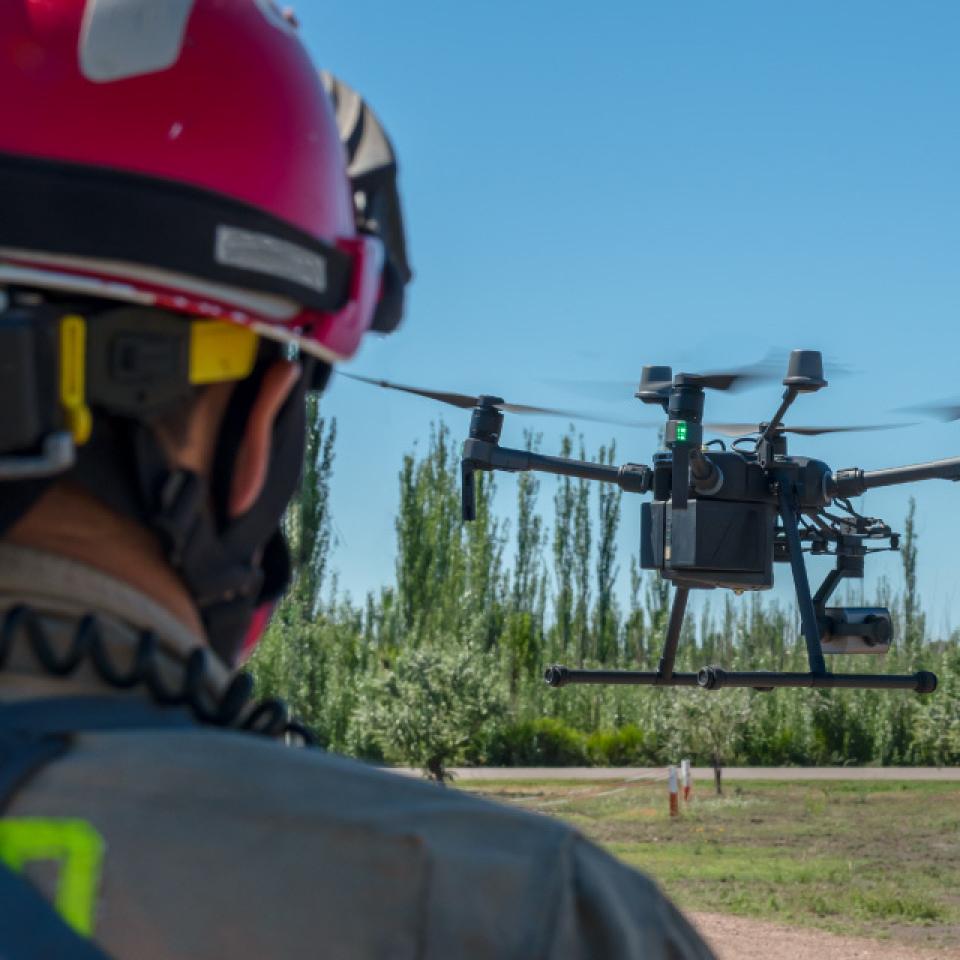 Ground school and certification: Firefighter with a helmet and a drone starting to fly from the ground.